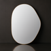 Modern organic-shaped wall mirror with a thin gold frame, reflecting light against a dark background.