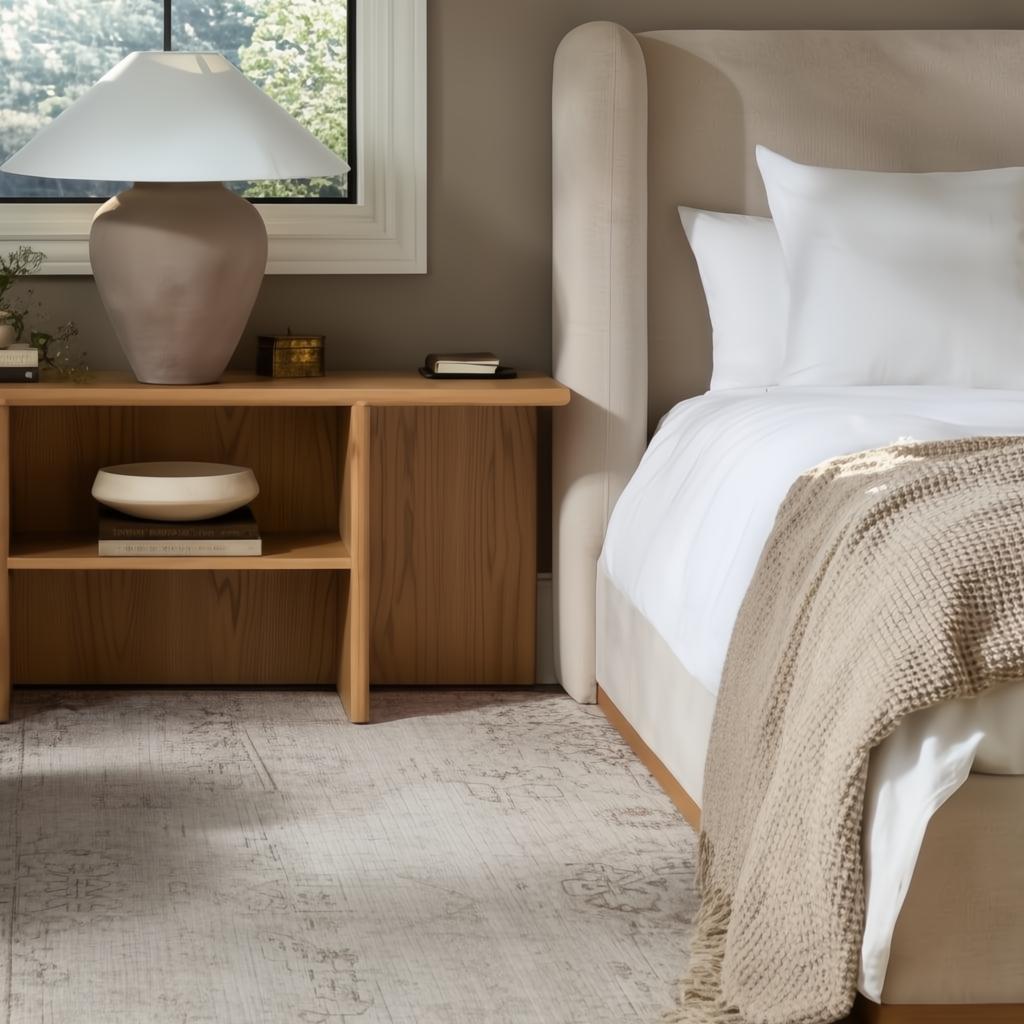 Beige upholstered bed with a tall headboard, white bedding, and a beige knitted throw.
