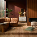 Brown leather Surya Oryan modular sofa with black rubber wood base in a modern living room.