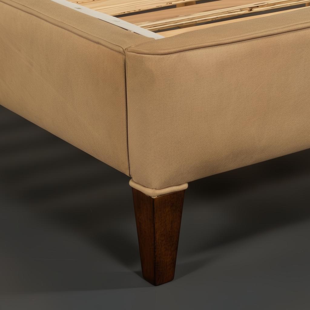 Close-up of a Surya Elipse upholstered bed base with light brown fabric and dark brown wood leg.