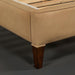 Close-up of a Surya Elipse upholstered bed base with light brown fabric and dark brown wood leg.