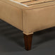 Close-up of a Surya Elipse upholstered bed base with light brown fabric and dark brown wood leg.