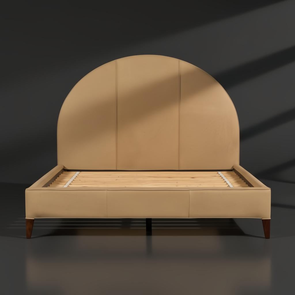 Surya Elipse upholstered bed with a rounded tan leather headboard and dark brown stained wooden legs.
