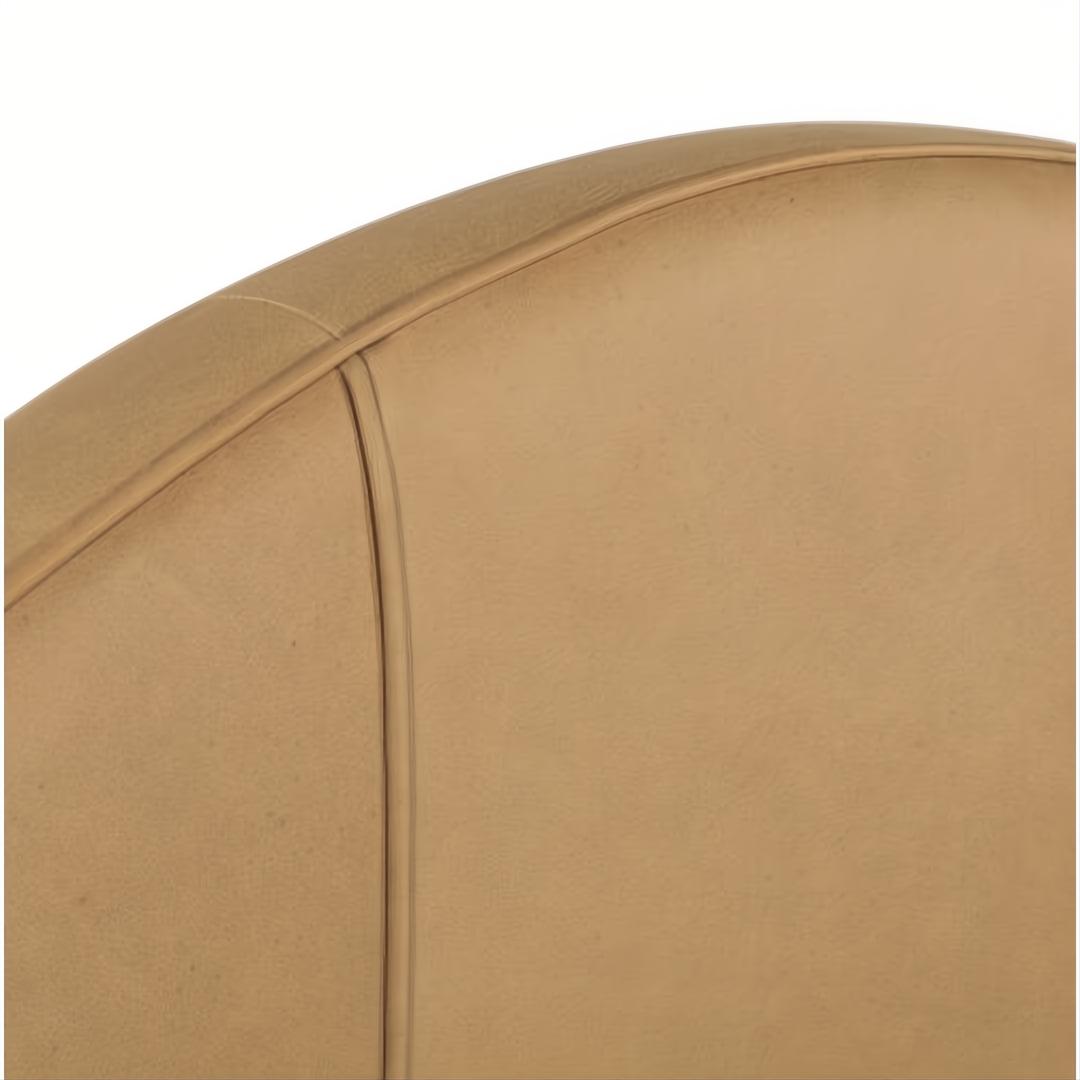 Close-up of a curved, light brown aniline dyed leather upholstered headboard with visible stitching.