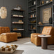 Two Surya Oryan modular chairs in brown leather with black bases, a round side table, and a bookshelf.