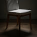Surya Joanne dining chair with off-white polyester upholstery and wheat rubber wood base on a wooden floor.
