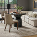 Two Surya Brooke dining chairs with medium brown polyester upholstery and wheat-finished beechwood bases, flanking a round black dining table.