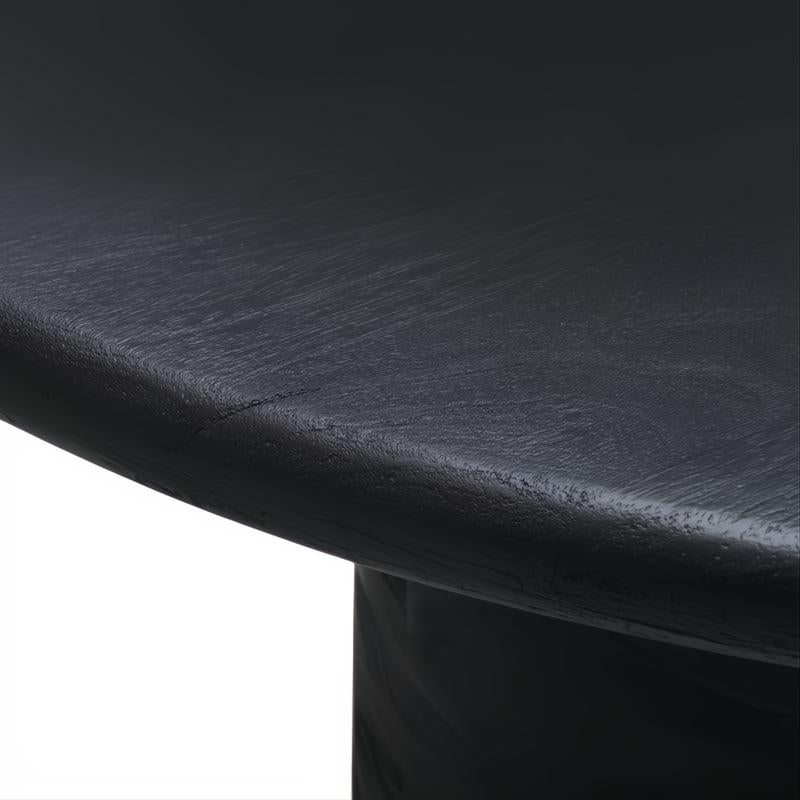 Close-up of a black brushed mango wood dining table with visible wood grain and a turned base.