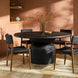 Surya Chia Dining Chair with brown stained ash wood base and black woven seat, paired with a round black dining table.