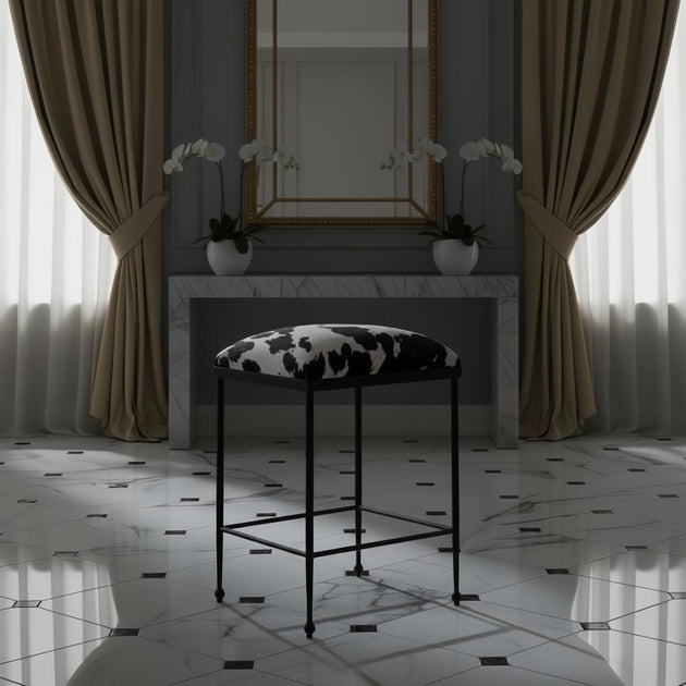 Surya Kornel counter stool with black iron frame and cowhide-patterned seat in a luxurious room.