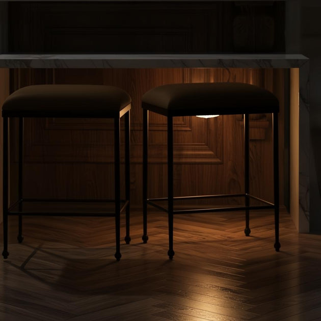 Two Surya Kornel counter stools with dark polyester seats and black powder-coated iron bases under a marble counter.