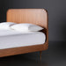 Brown stained poplar wood bed with a minimalist modern design and slatted headboard.
