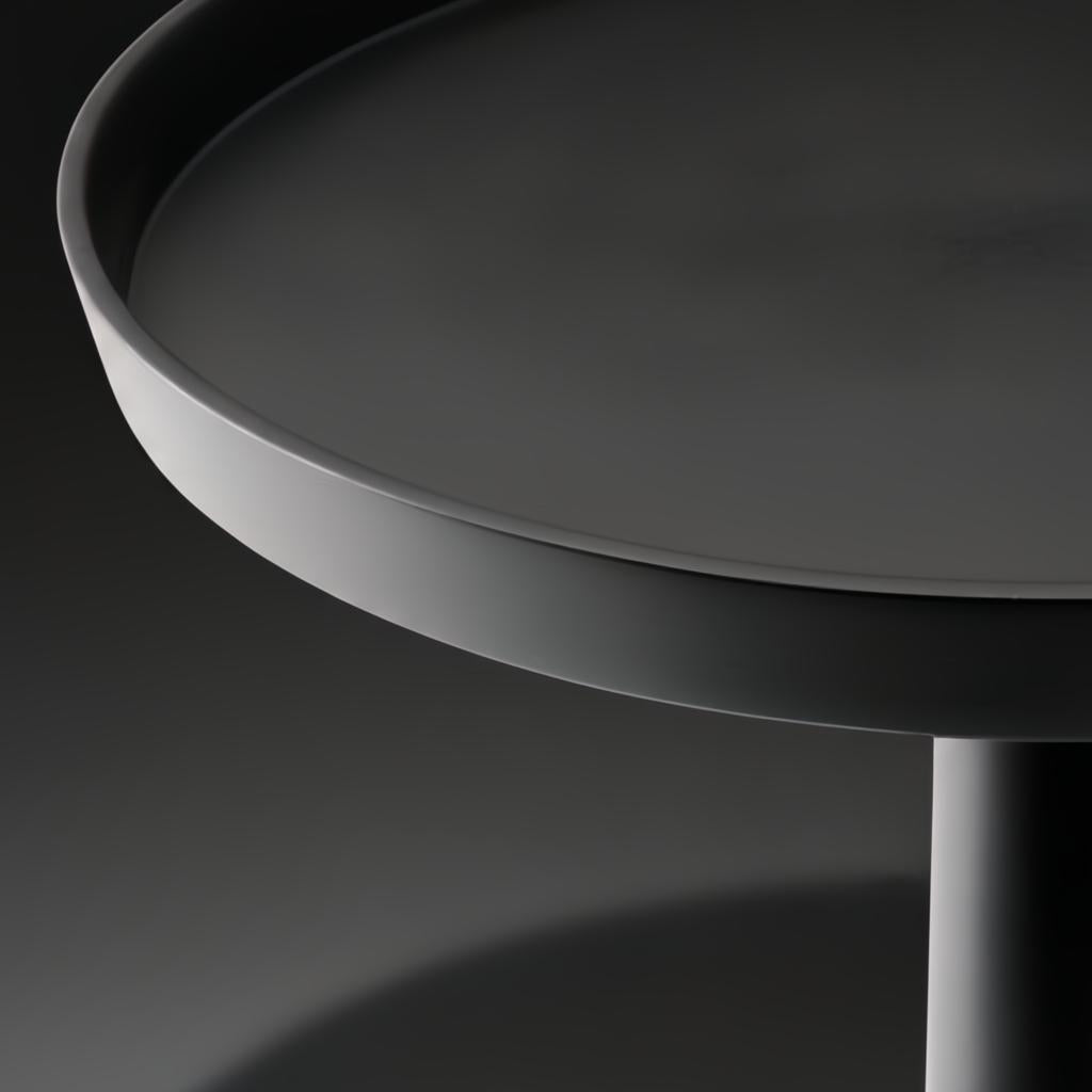 Close-up of a black aluminum Surya Molino end table with a round top and pedestal base.