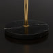 Close-up of a round black natural marble base with white veining and a brass-colored stand.