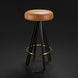 Surya Oberon backless bar stool with brown leather seat, black steel base, and brass footrest.