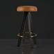 Surya Oberon backless bar stool with brown leather seat, black steel base, and gold footrest.