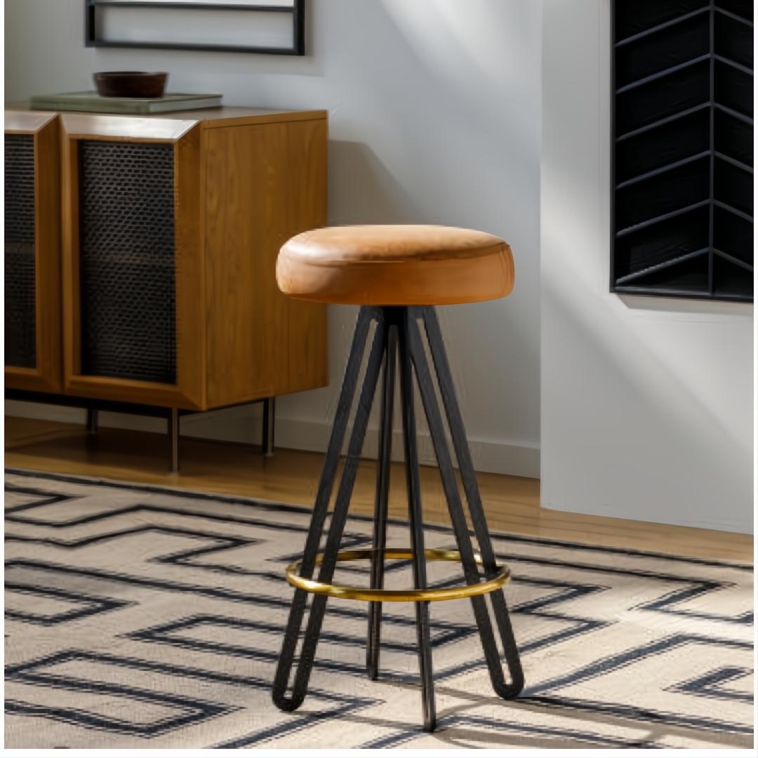Surya Oberon backless bar stool with brown leather seat, black steel base, and gold footrest.