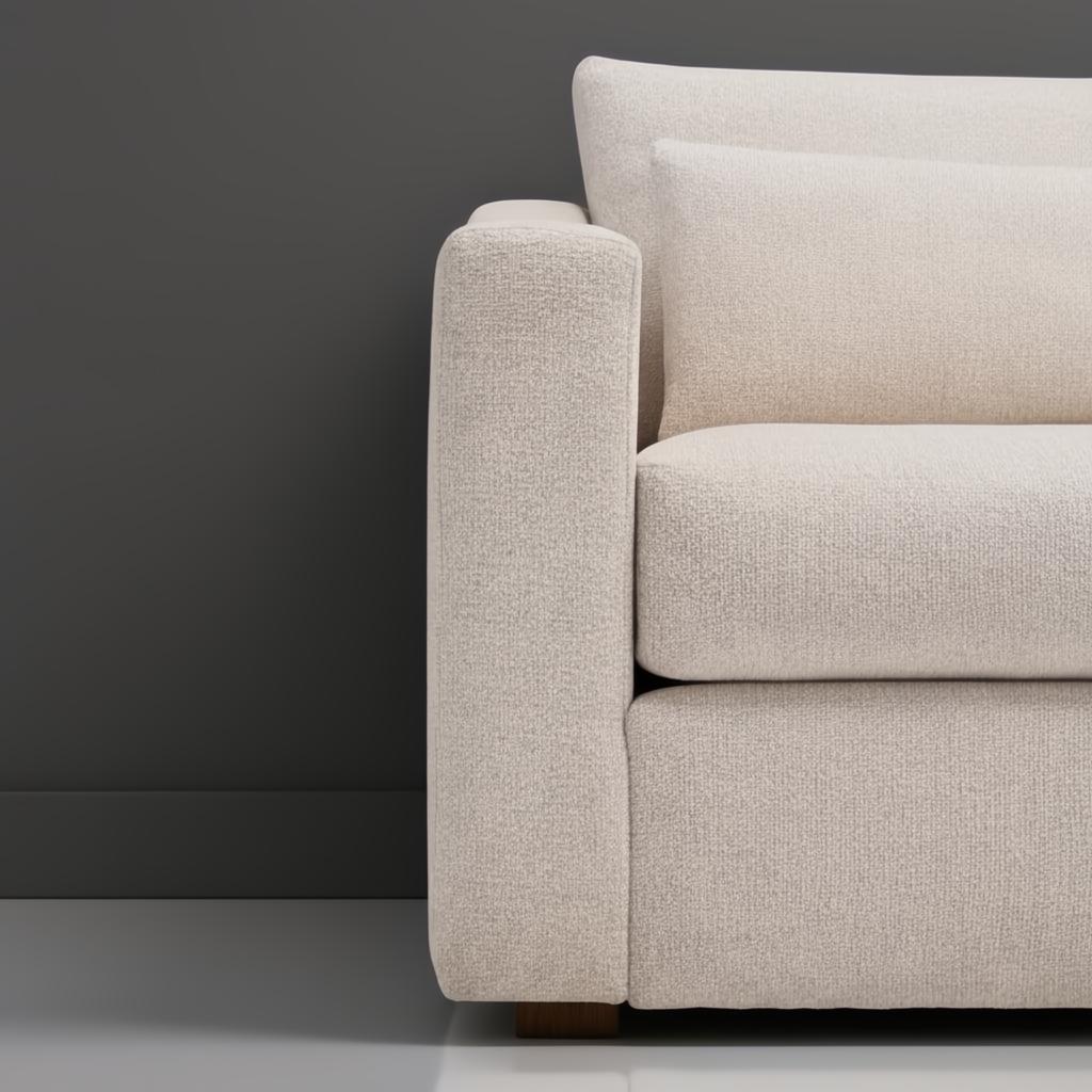 Close-up of a light beige textured polyester sofa arm and cushions against a dark gray wall.