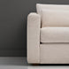 Close-up of a light beige textured polyester sofa arm and cushions against a dark gray wall.