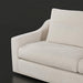 Close-up of a light beige fabric sofa with a curved armrest and a rectangular throw pillow.