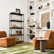Brown leather modular sofa chairs with black rubber wood bases in a modern living room.