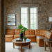 Surya Oryan modular sofa in brown leather, with a round wooden coffee table and accent table.